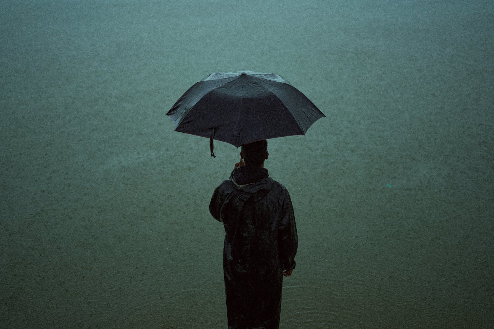 person in black raincoat holding an umbrella