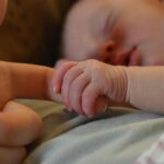 baby holding human finger