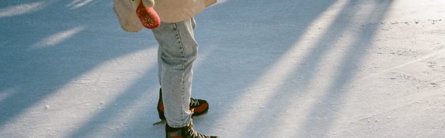 faceless fit woman skating on ice rink in daylight