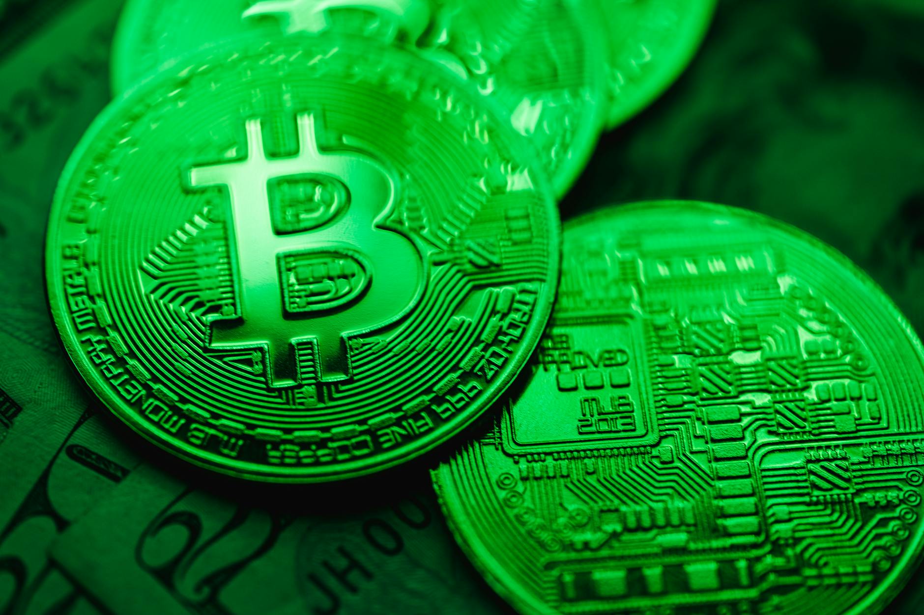 closeup of bit coins in a green light