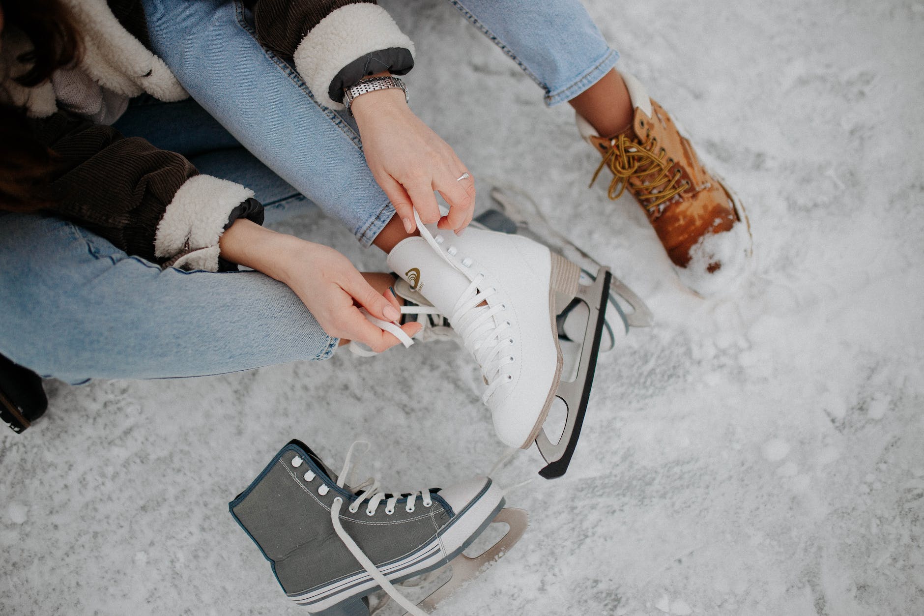 women tying shoelaces on ice skates
