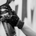 grayscale photo of a hand holding a spray can