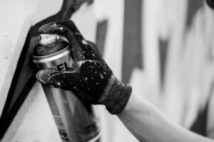 grayscale photo of a hand holding a spray can